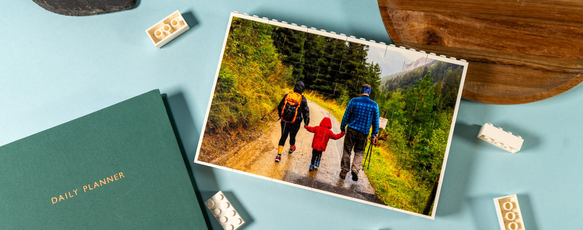A personalised photo block made of LEGO® bricks with a family photo on, surrounded by a daily planner book and wooden tray on a desk