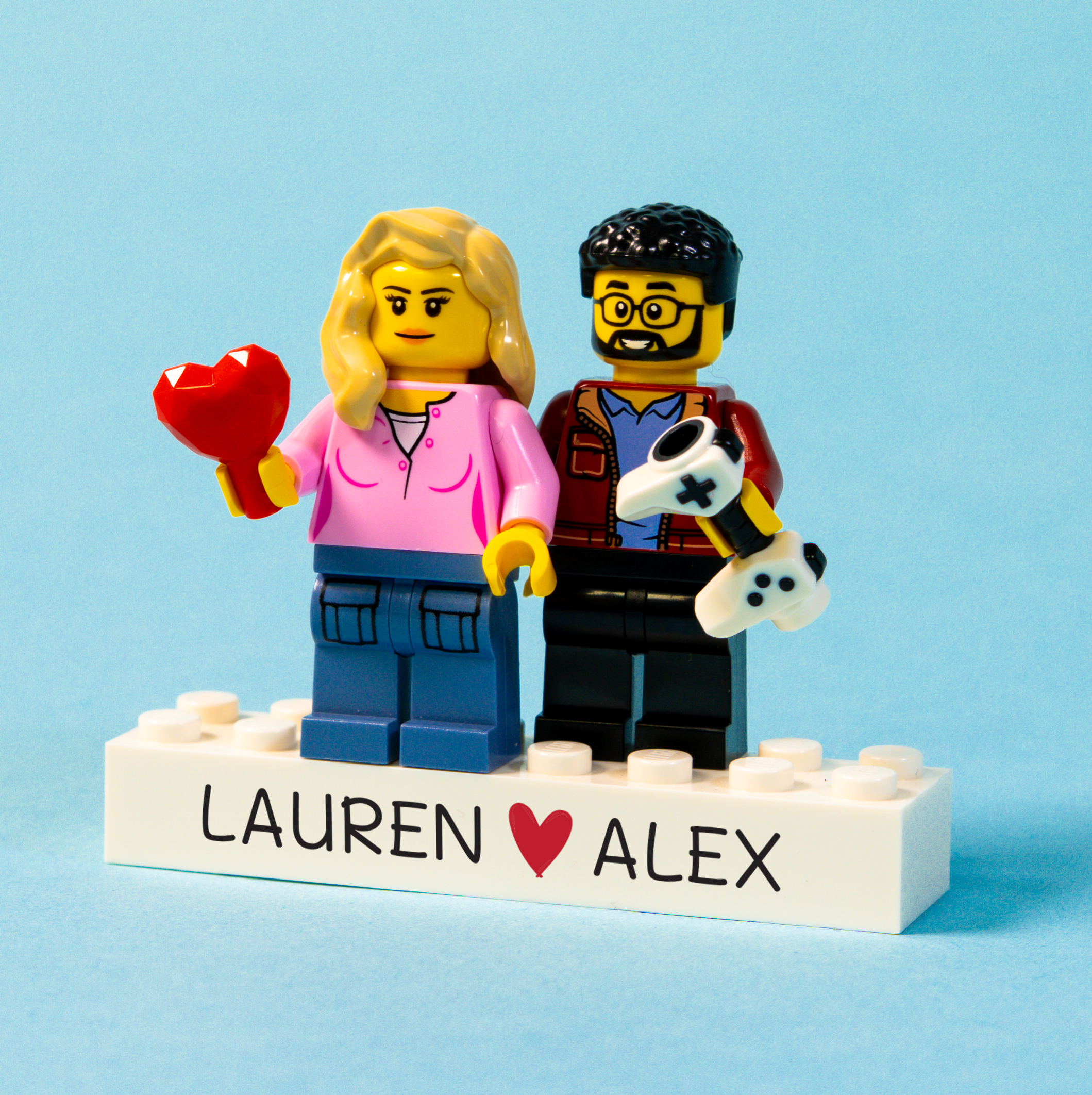 Two LEGO figures of a couple with a heart on a blue background