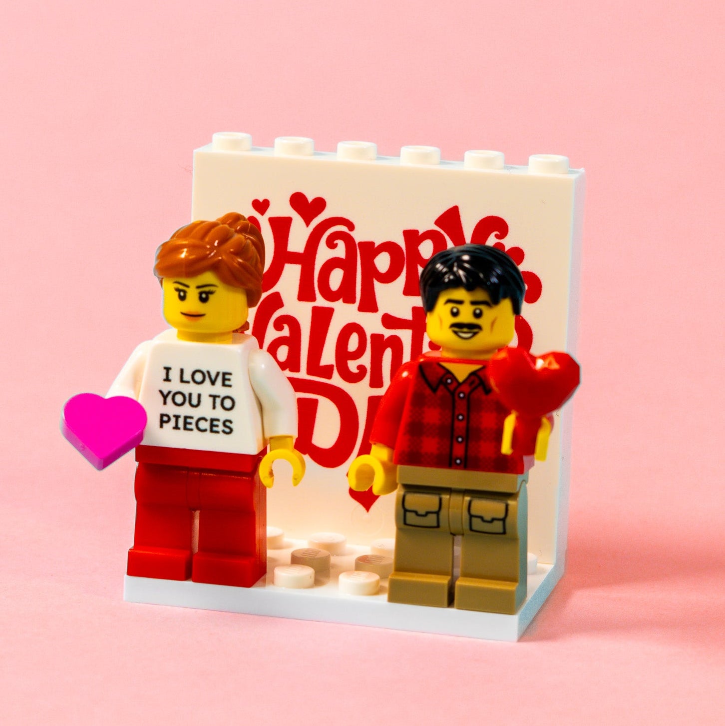 Two personalised LEGO brick figures with a 'Happy Valentine's Day' sign on a pink background