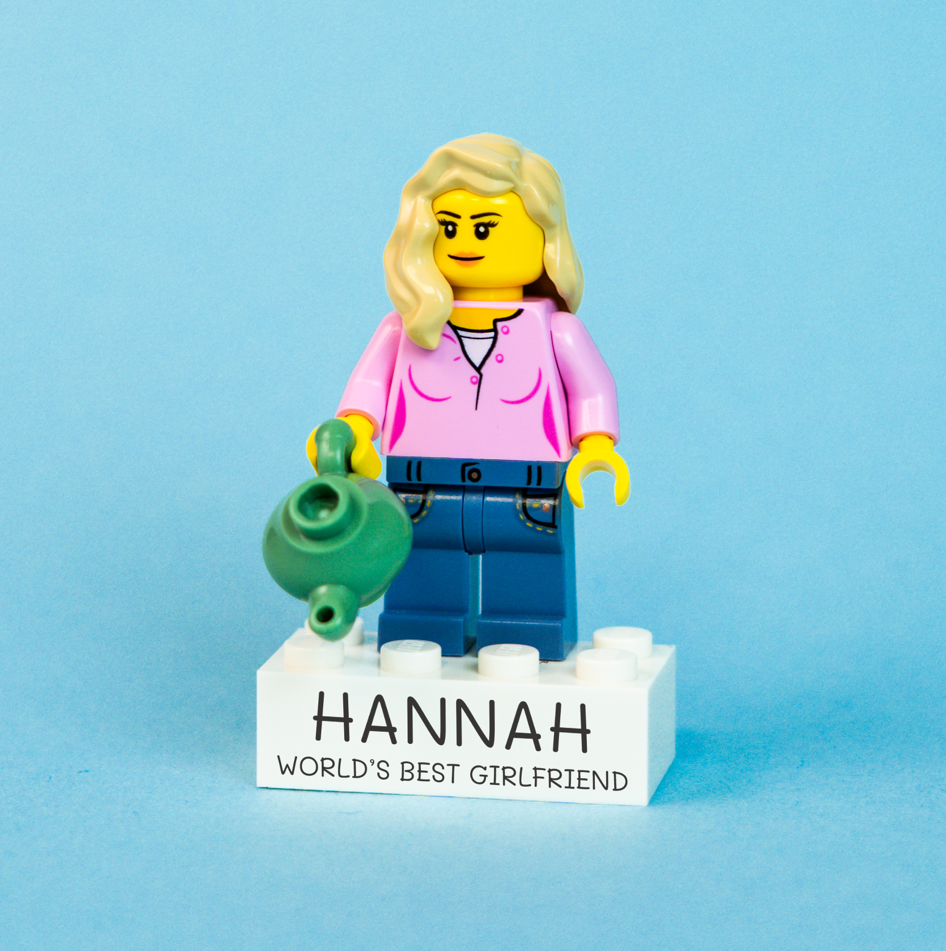 LEGO brick figure of a woman named Hannah holding a green tea pot on a blue background