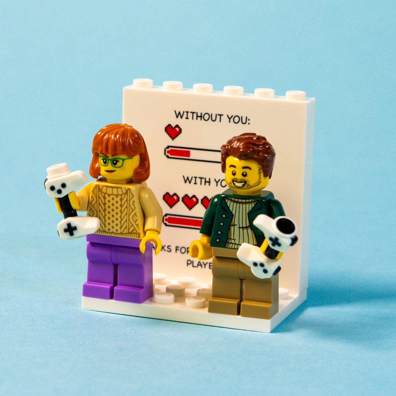 LEGO figures with a personalised gamer themed heart photo wall on a blue background